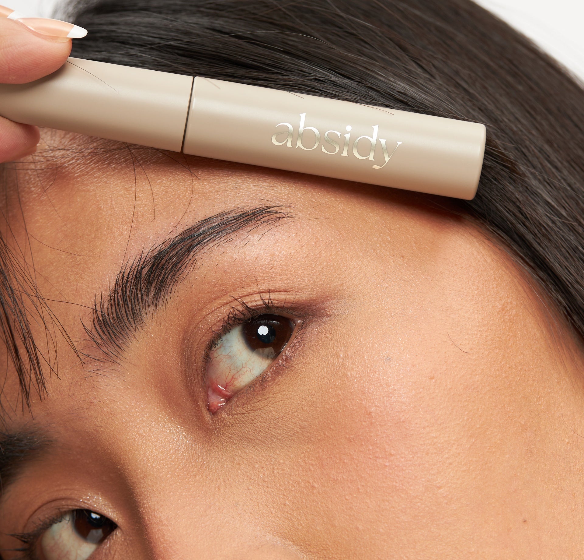 Person applying concealer to their under-eye area with a makeup brush.
